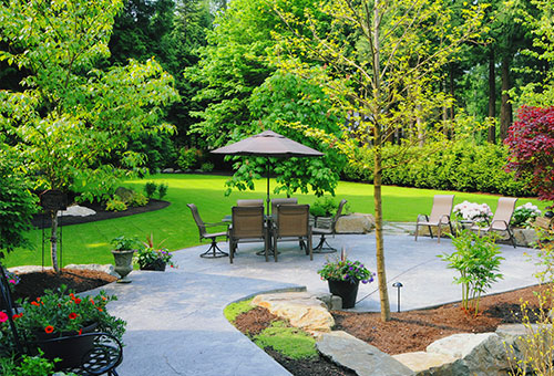 landscaping and patio with table and chairs with umbrella