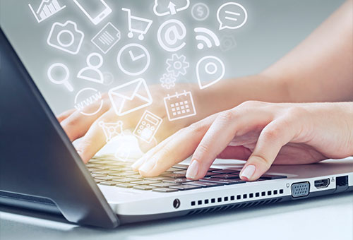 Hands typing on a laptop keyboard with various digital icons, such as email, calendar, shopping cart, and cloud, appearing above the screen, symbolizing online communication and technology.